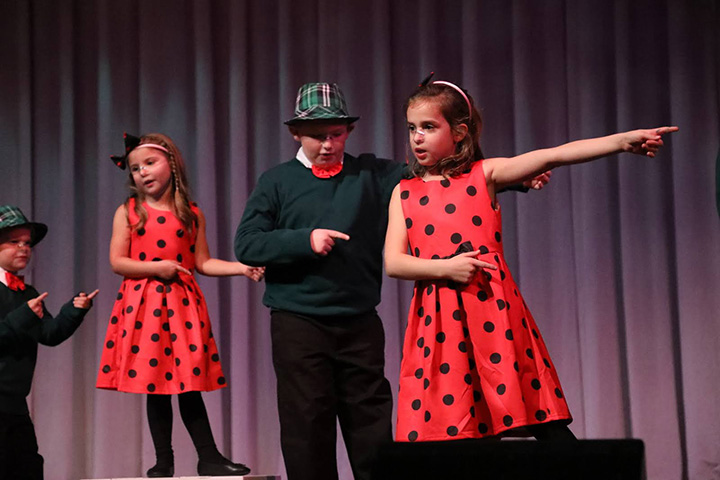 Young children wearing holiday dress-up outfit gesturing to the right